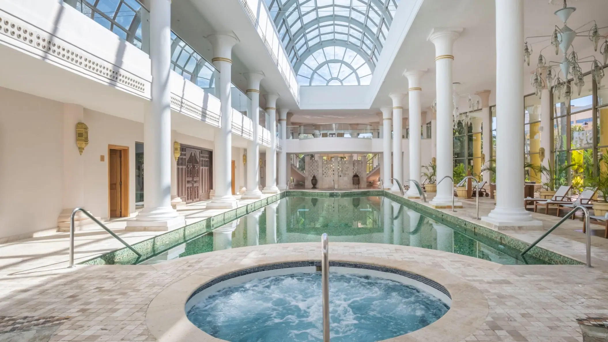 Indoor pool and spa area with white columns and a glass vaulted ceiling at JOIA Paraiso by Iberostar, Riviera Maya
