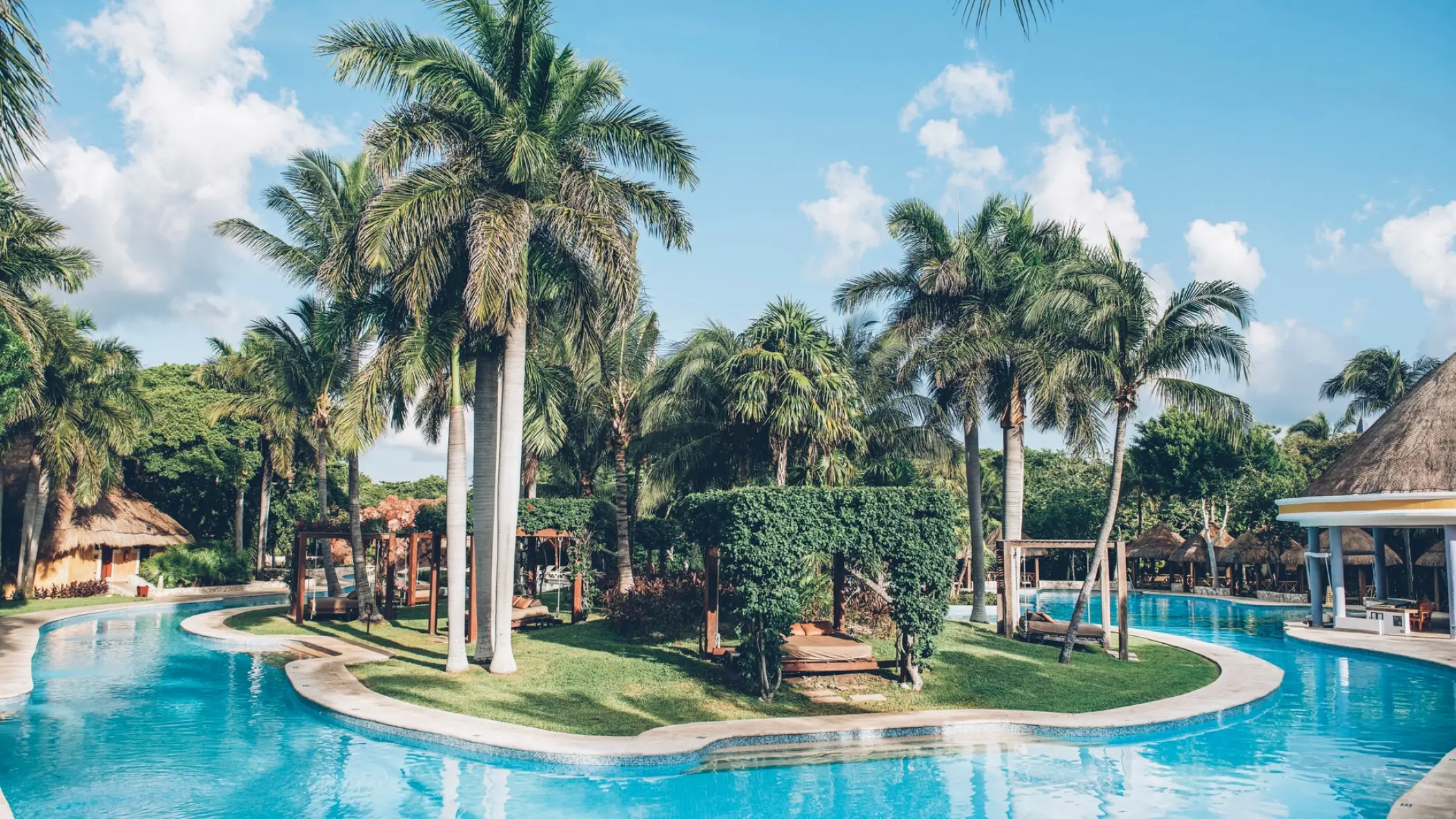 Winding lagoon pool surrounded by palm trees and tropical gardens at Iberostar Paraiso Beach, Riviera Maya