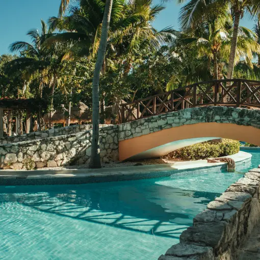 Stone arched bridge over a tropical pool at Iberostar Paraiso Del Mar, Riviera Maya