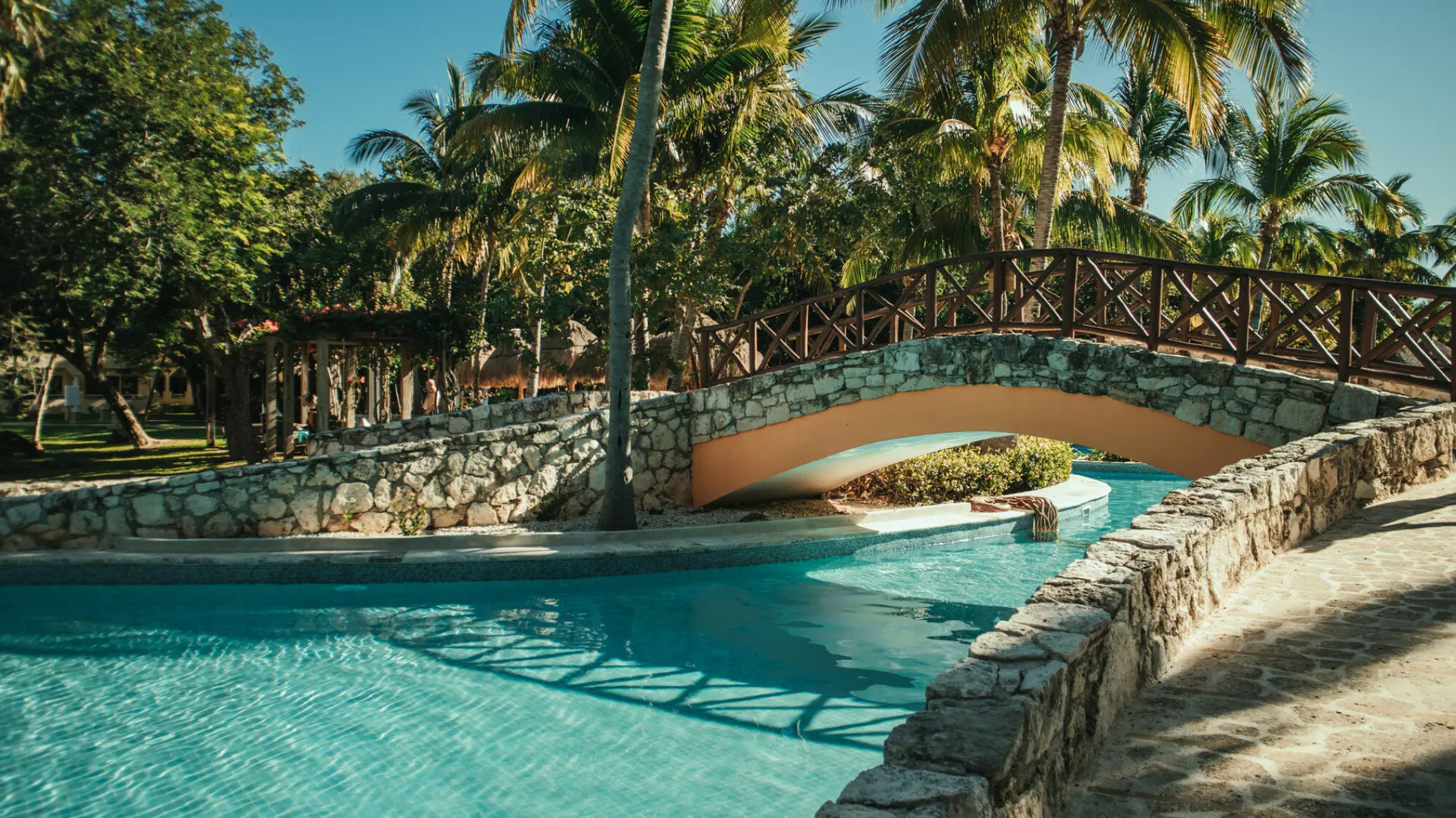 Stone arched bridge over a tropical pool at Iberostar Paraiso Del Mar, Riviera Maya