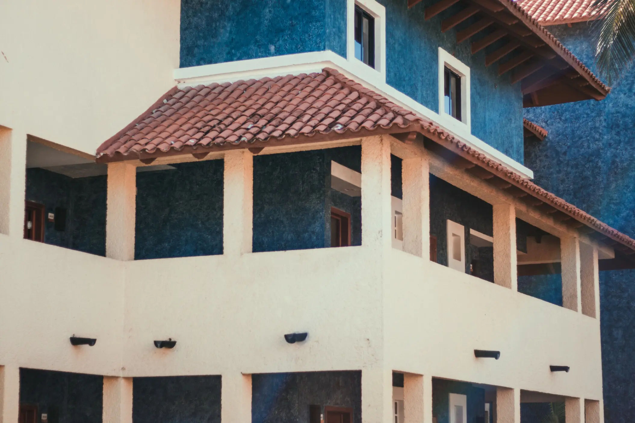 Terracotta tiled roof and blue stone walls of guest room balconies at Iberostar Paraiso Del Mar, Riviera Maya