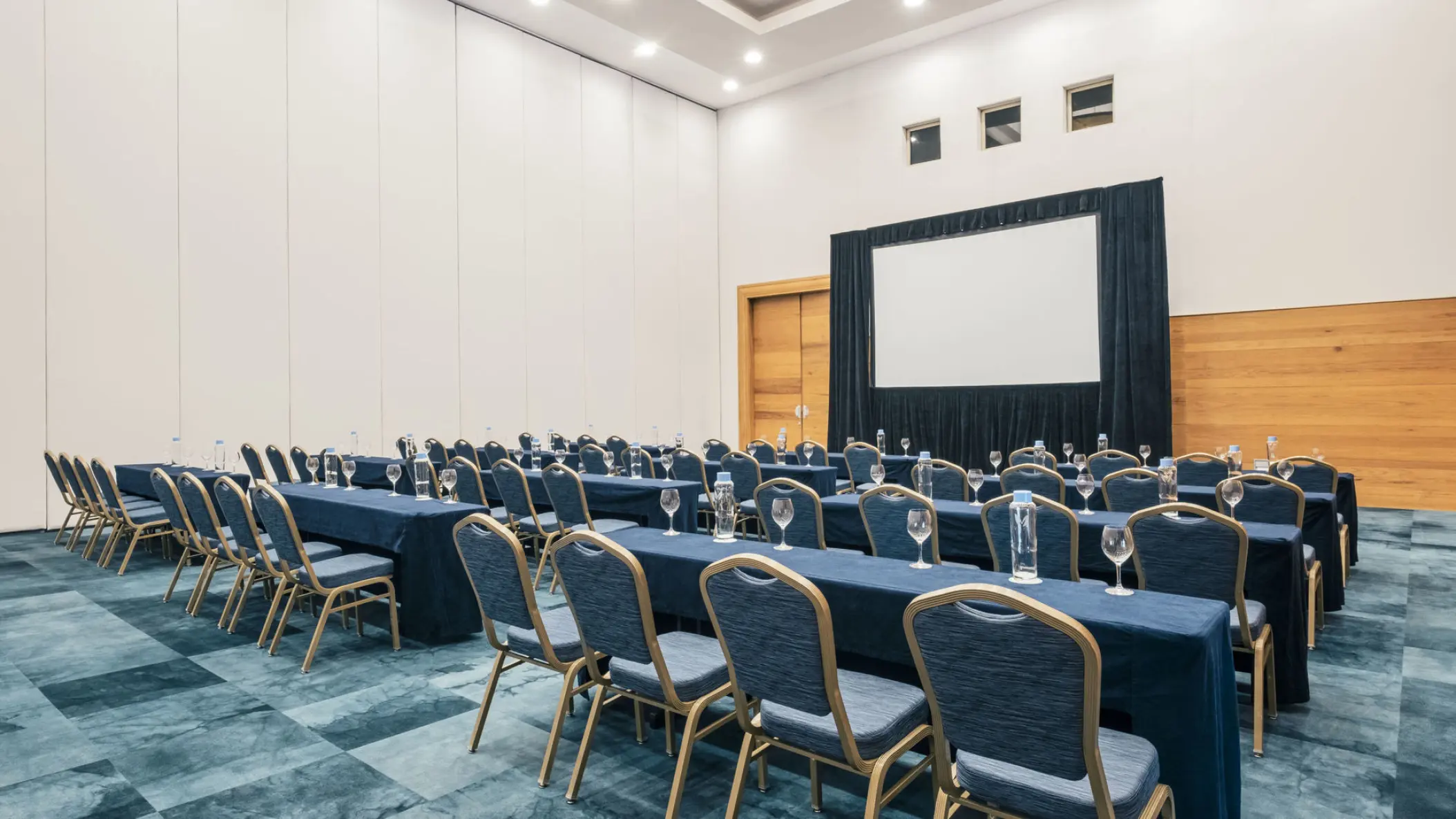 Indoor convention center with rows of tables and a projection screen at Iberostar Selection Paraiso Lindo, Riviera Maya
