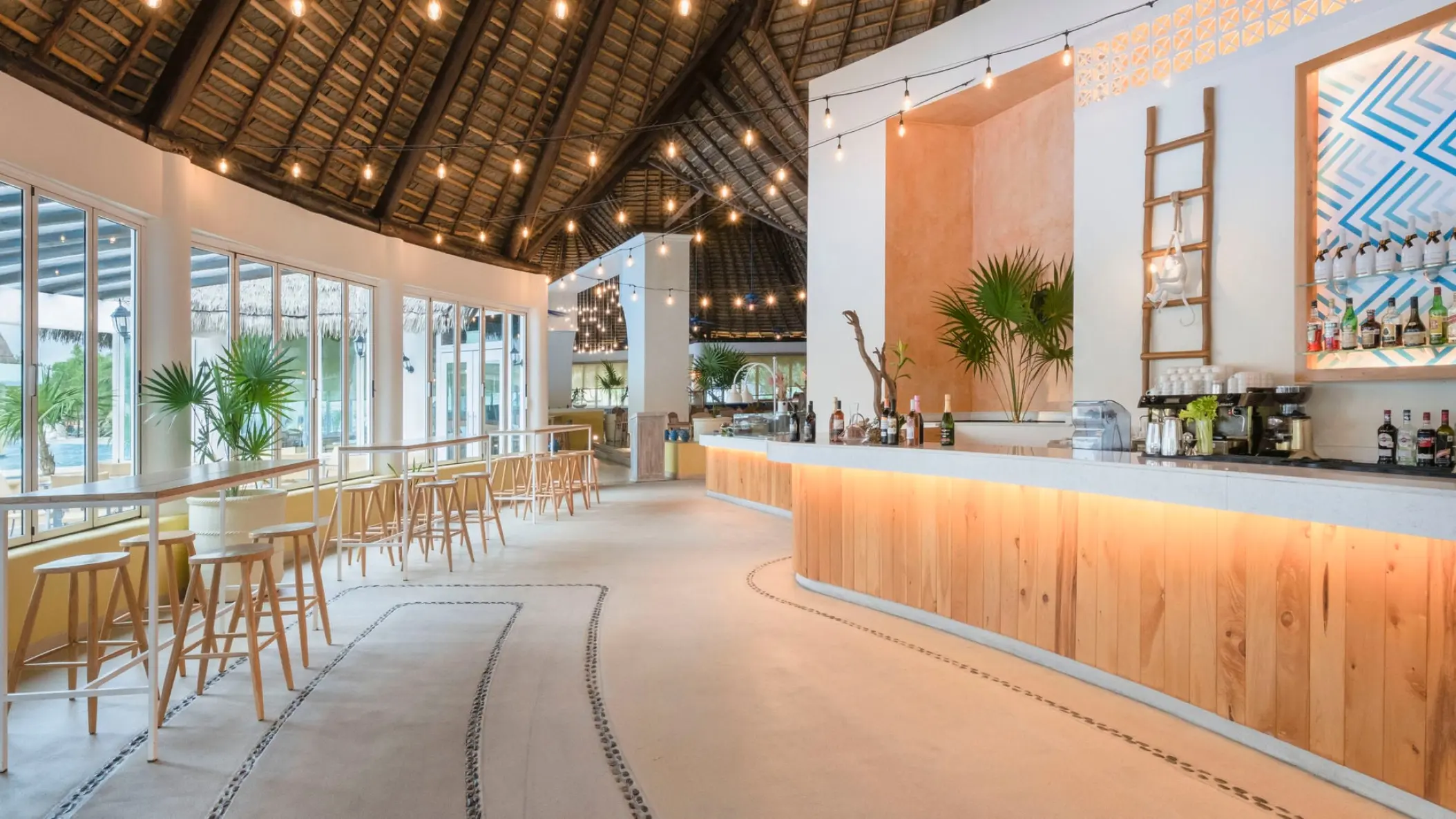 Modern open-air restaurant bar with a thatched roof and string lights at Iberostar Paraiso Lindo, Riviera Maya