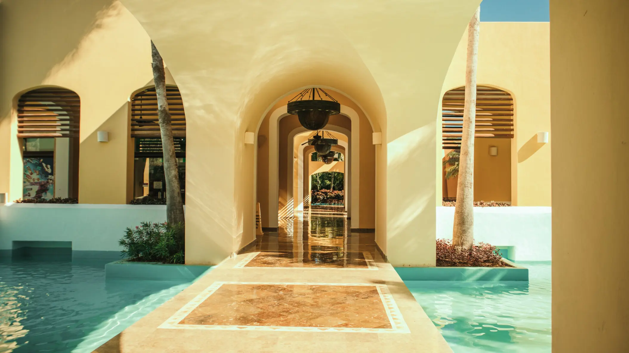 Arched stone hallway surrounded by turquoise pools at Iberostar Paraiso Maya, Riviera Maya