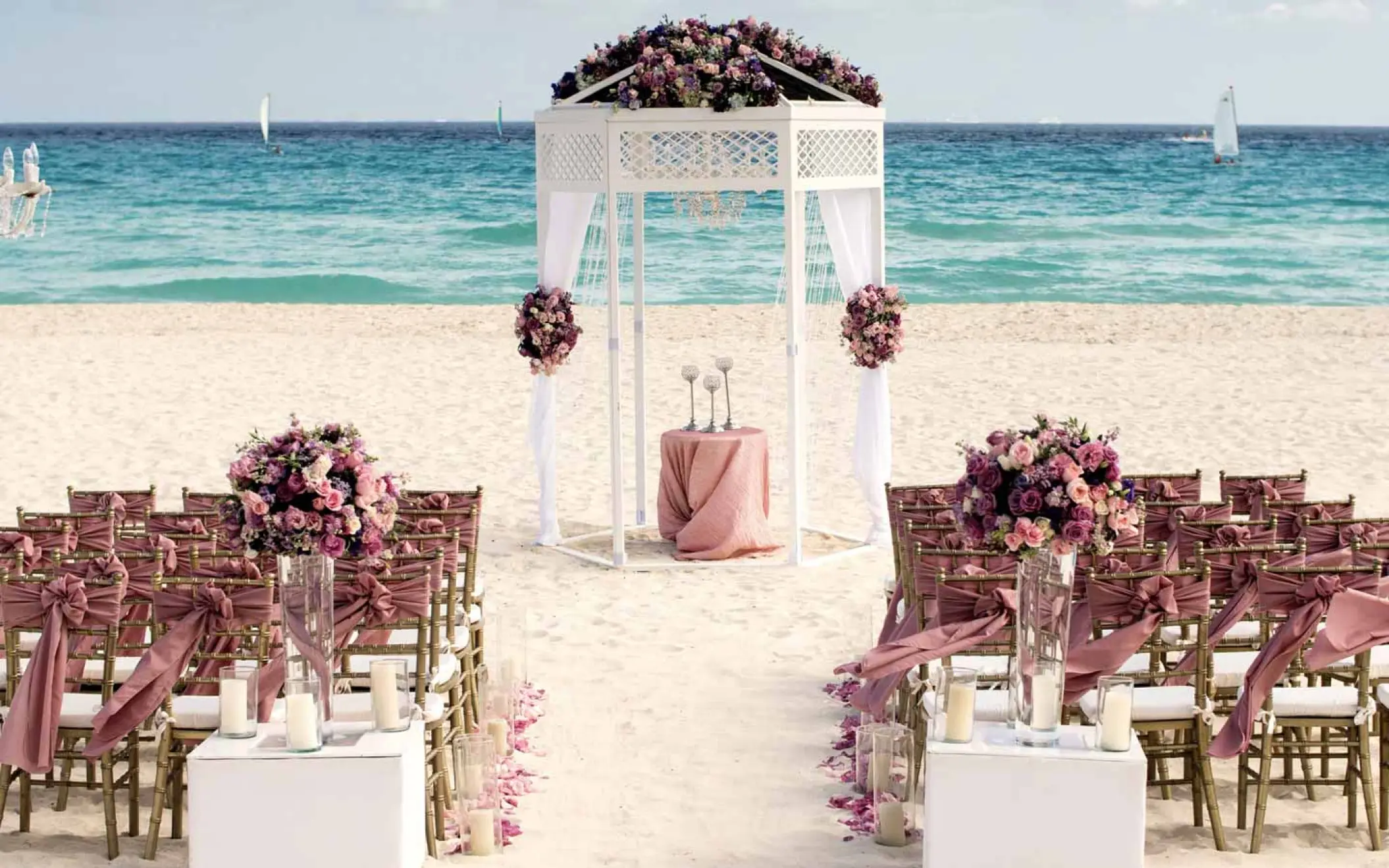 Beachfront wedding ceremony setup with white gazebo and pink flowers at Iberostar Quetzal, Playa Del Carmen