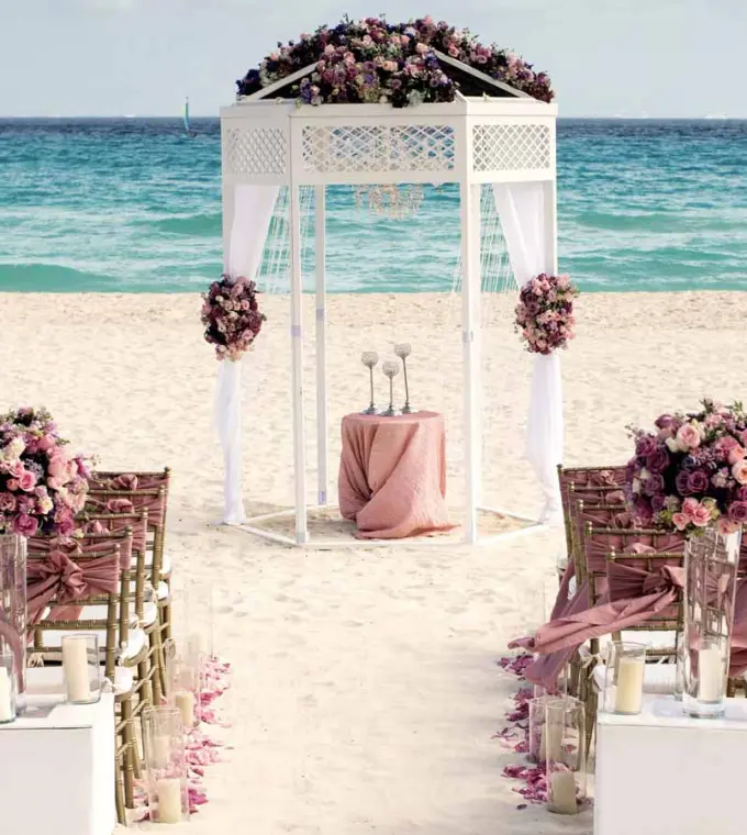 Beachfront wedding ceremony setup with white gazebo and pink flowers at Iberostar Quetzal, Playa Del Carmen