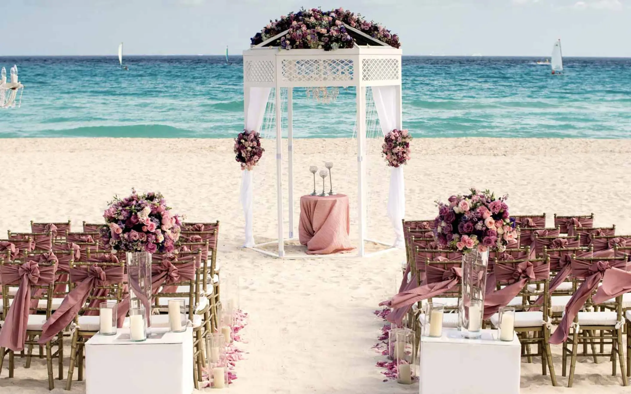 Beachfront wedding ceremony setup with white gazebo and pink flowers at Iberostar Quetzal, Playa Del Carmen