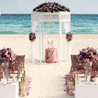 Beachfront wedding ceremony setup with white gazebo and pink flowers at Iberostar Quetzal, Playa Del Carmen