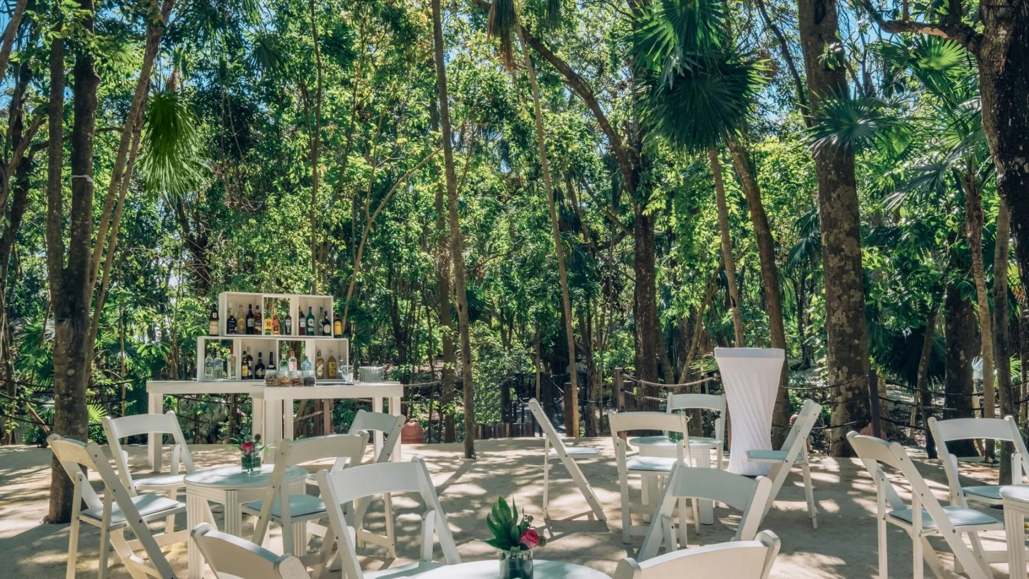 Garden wedding reception with white chairs and bar at Iberostar Waves Quetzal, Playa Del Carmen