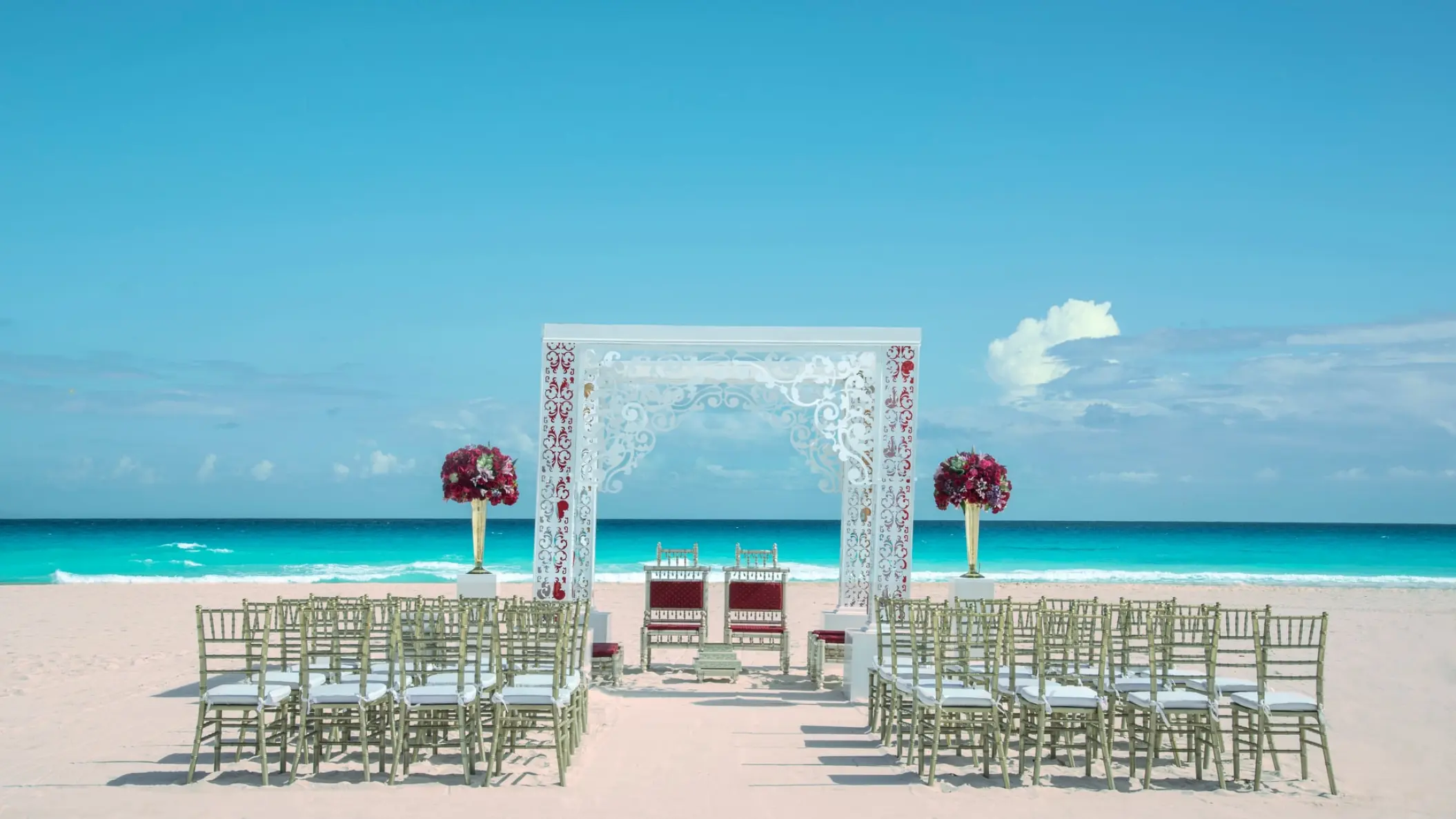 Beachfront wedding ceremony with a white laser-cut gazebo at Iberostar Selection Cancun