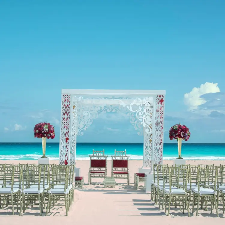 Beachfront wedding ceremony with a white laser-cut gazebo at Iberostar Selection Cancun