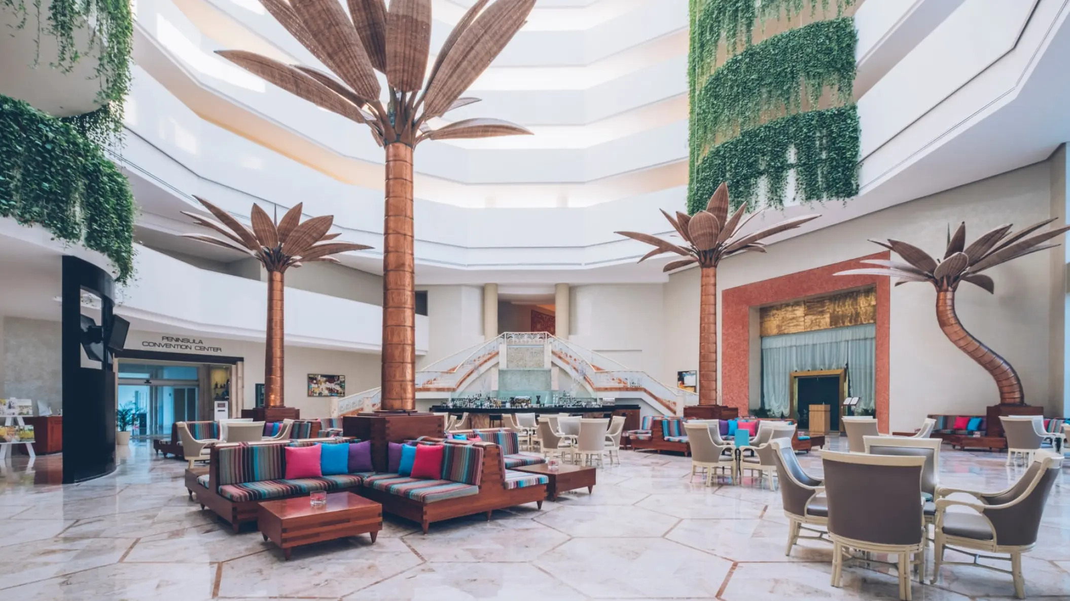 Atrium lobby lounge with palm tree sculptures and colorful seating at Iberostar Selection Cancun