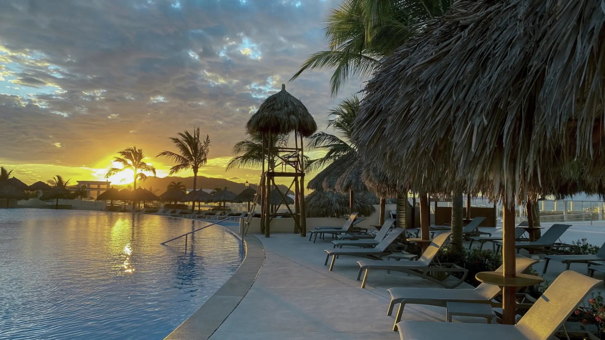 Iberostar Selection Playa Mita main pool at sunset with palapa umbrellas and lounge chairs, Puerto Vallarta