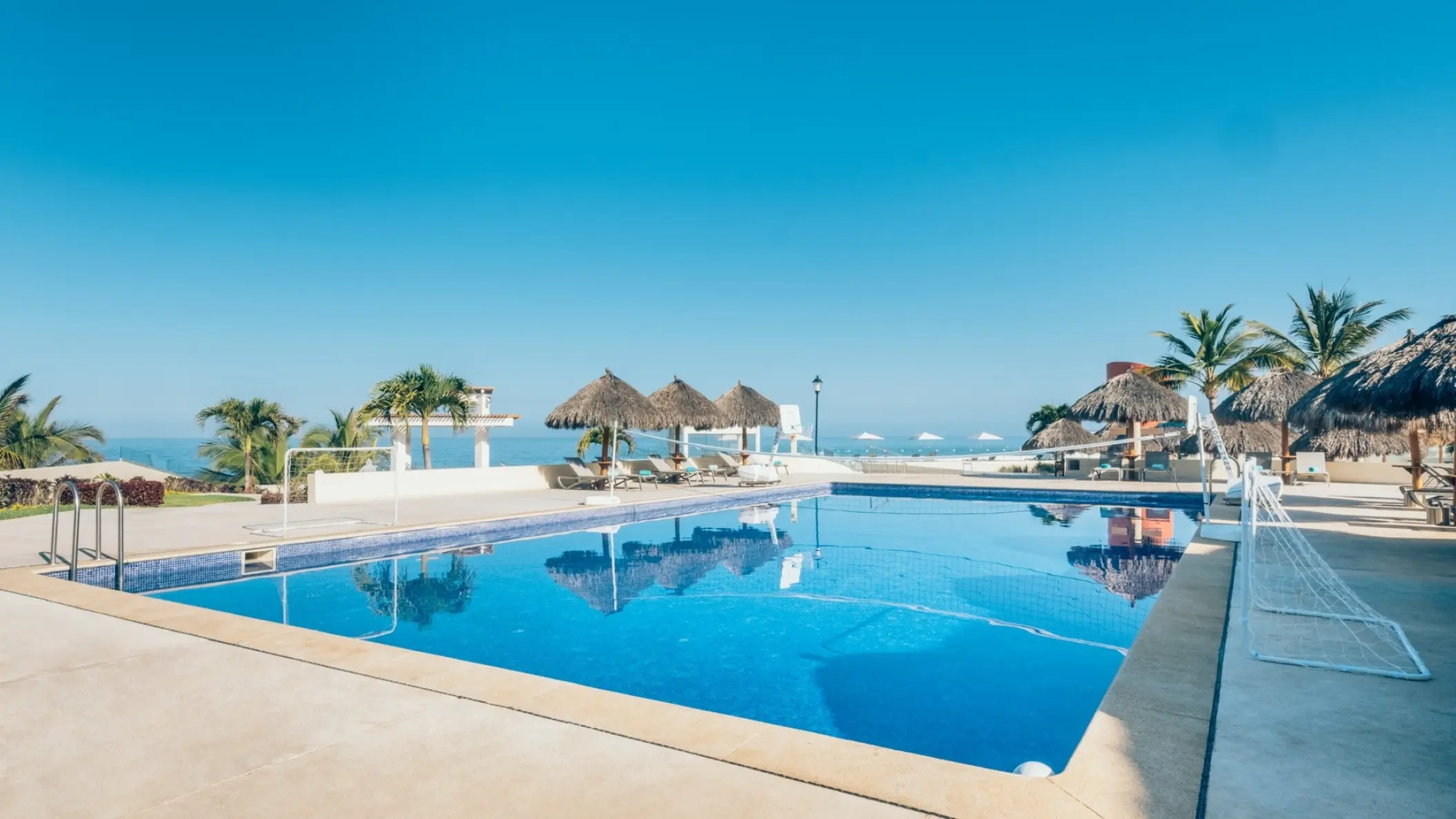 Main swimming pool with volleyball net and thatched umbrellas at Iberostar Selection Playa Mita, Puerto Vallarta
