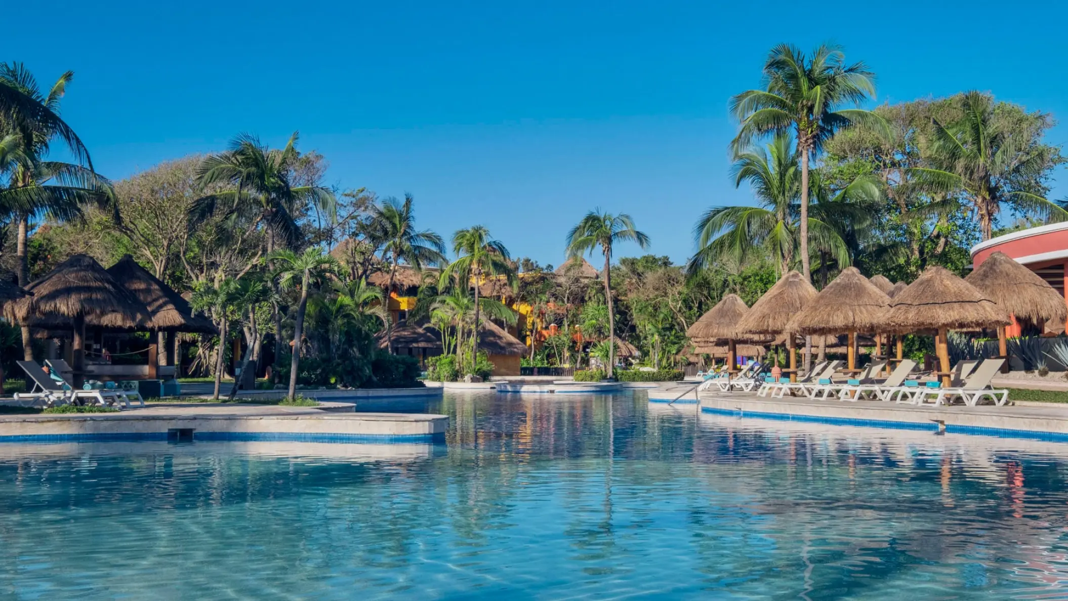 Iberostar Tucan swimming pool surrounded by palapas and palm trees, Playa Del Carmen