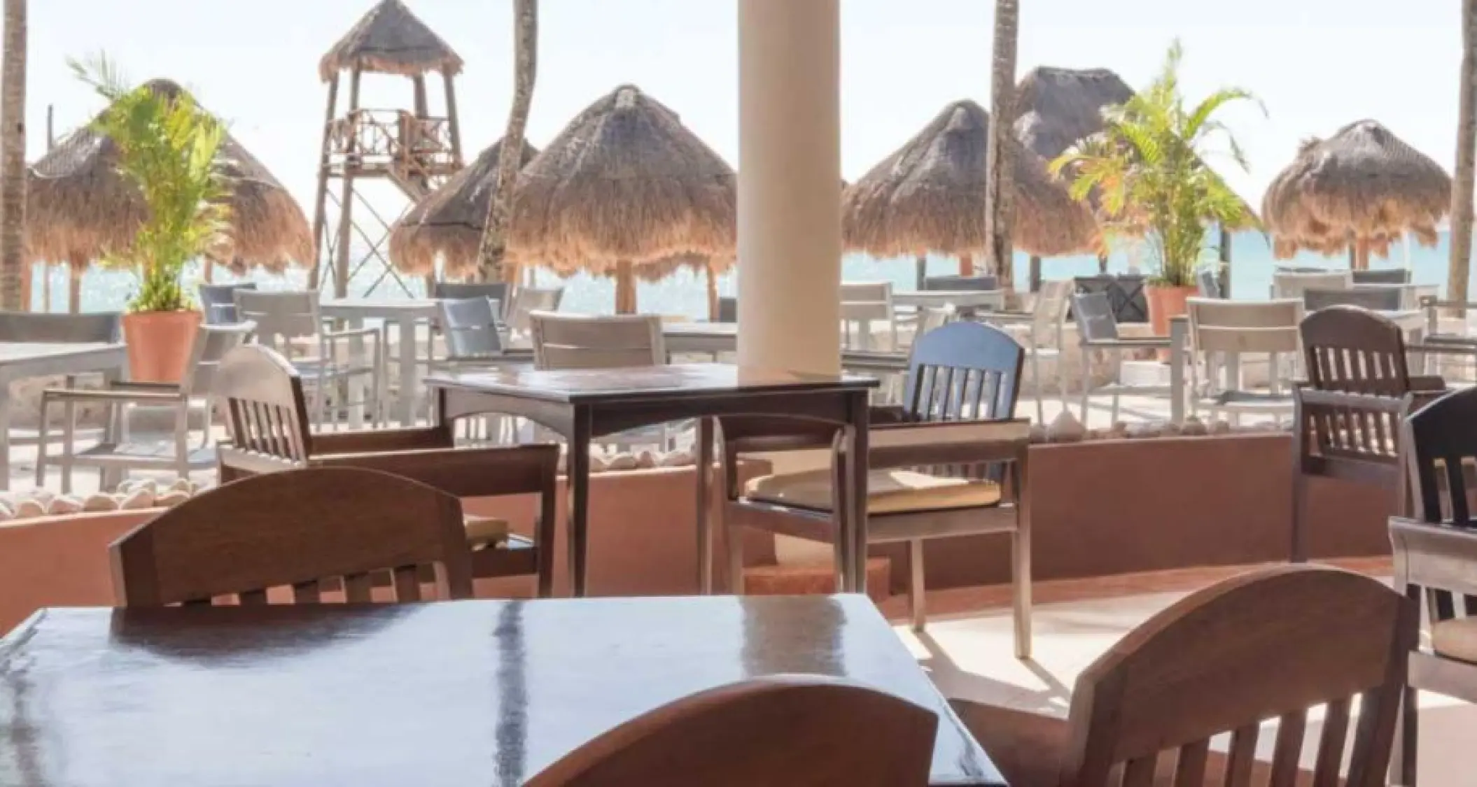 Outdoor restaurant tables overlooking beach palapas at Iberostar Waves Tucan, Playa Del Carmen