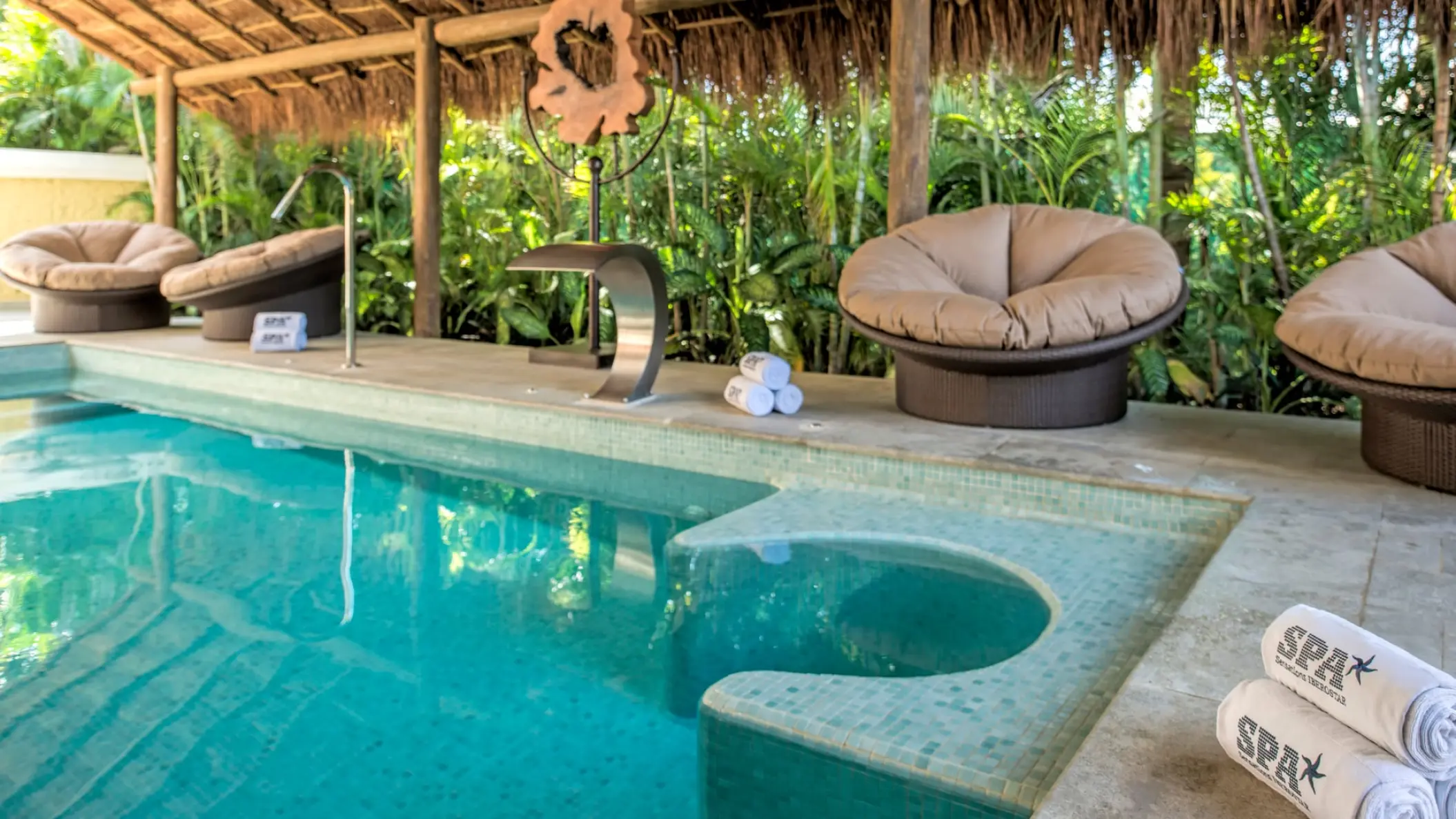 Outdoor spa pool with lounge seating under a thatched roof at Iberostar Waves Tucan, Playa Del Carmen
