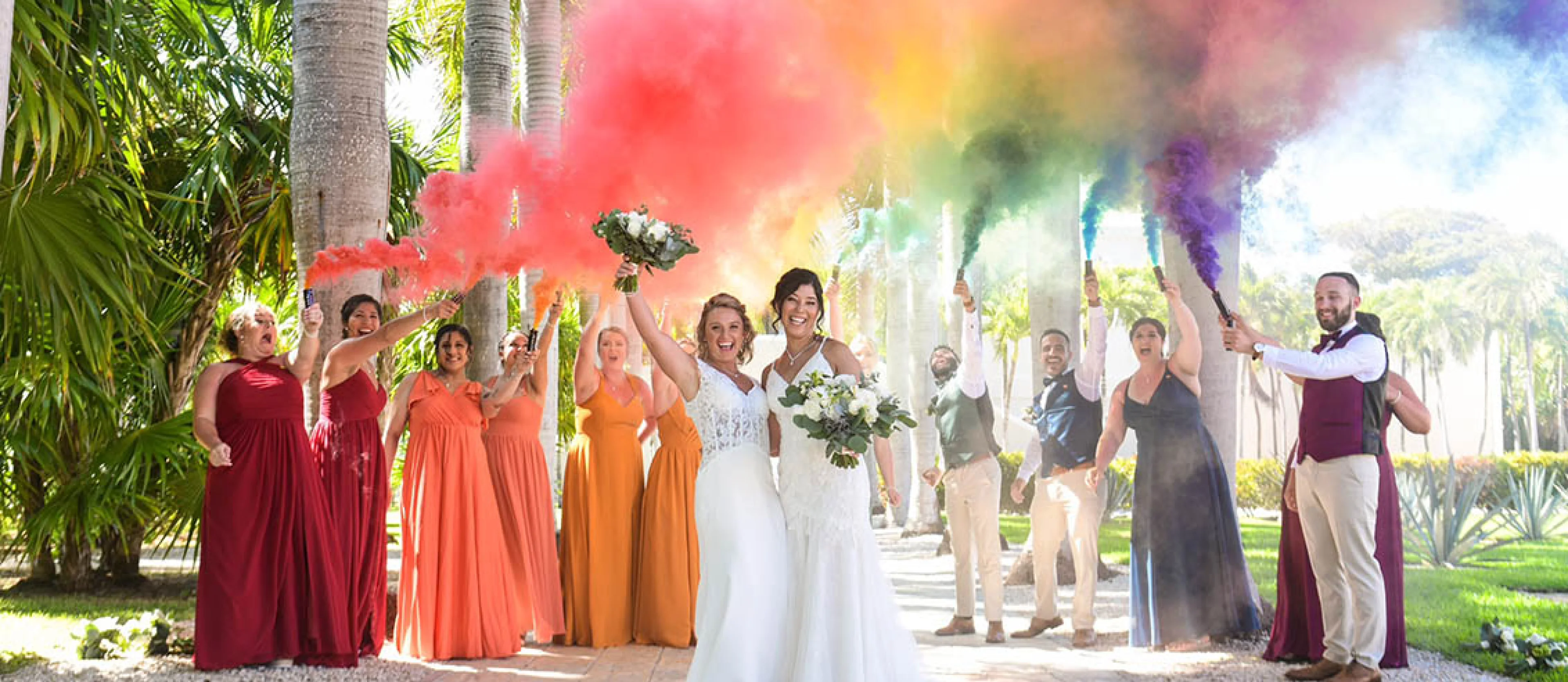 tw brides celebrate their wedding with their wedding party and rainbow color smoke