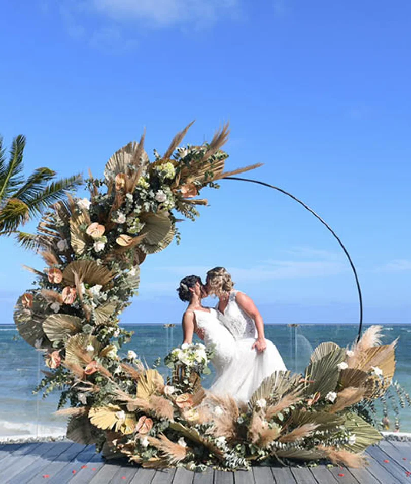 two newlywed brides kiss on a beautiful isle on the beach