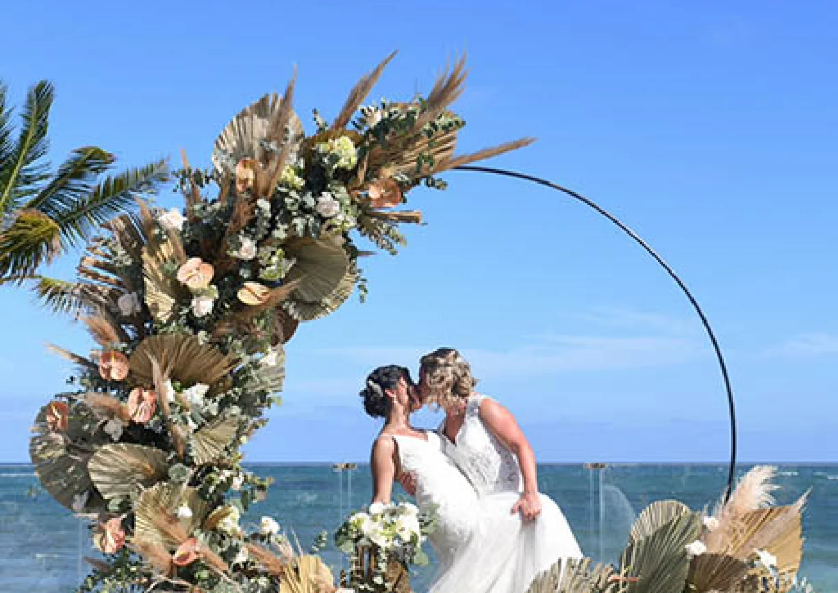 two newlywed brides kiss on a beautiful isle on the beach
