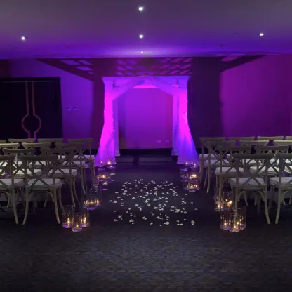 Indoor ballroom wedding ceremony with purple lighting and white fabric arch at Le Blanc Los Cabos, Cabo San Lucas