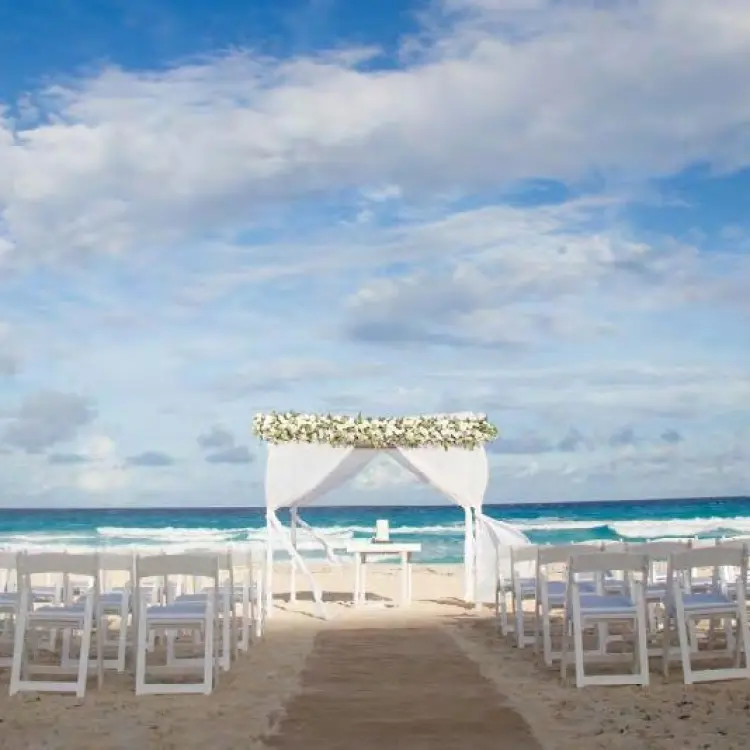 Beachfront wedding ceremony with white huppah and chairs at Live Aqua Cancun