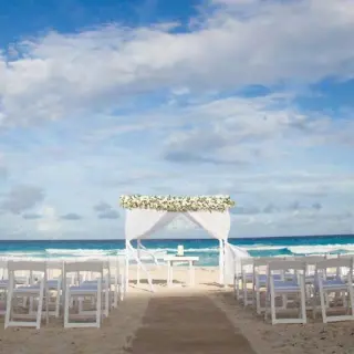 Beachfront wedding ceremony with white huppah and chairs at Live Aqua Cancun