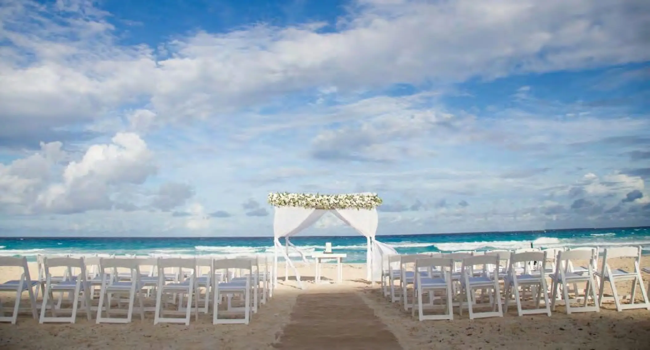 Beachfront wedding ceremony with white huppah and chairs at Live Aqua Cancun