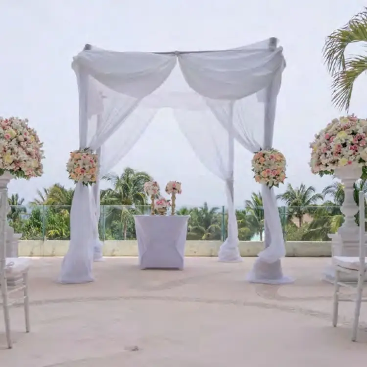 Outdoor terrace wedding ceremony setup with white draped chuppah and floral spheres at Live Aqua Cancun