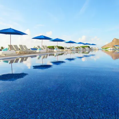 Blue umbrellas and lounge chairs reflected in the infinity pool at Live Aqua Beach Resort, Cancun