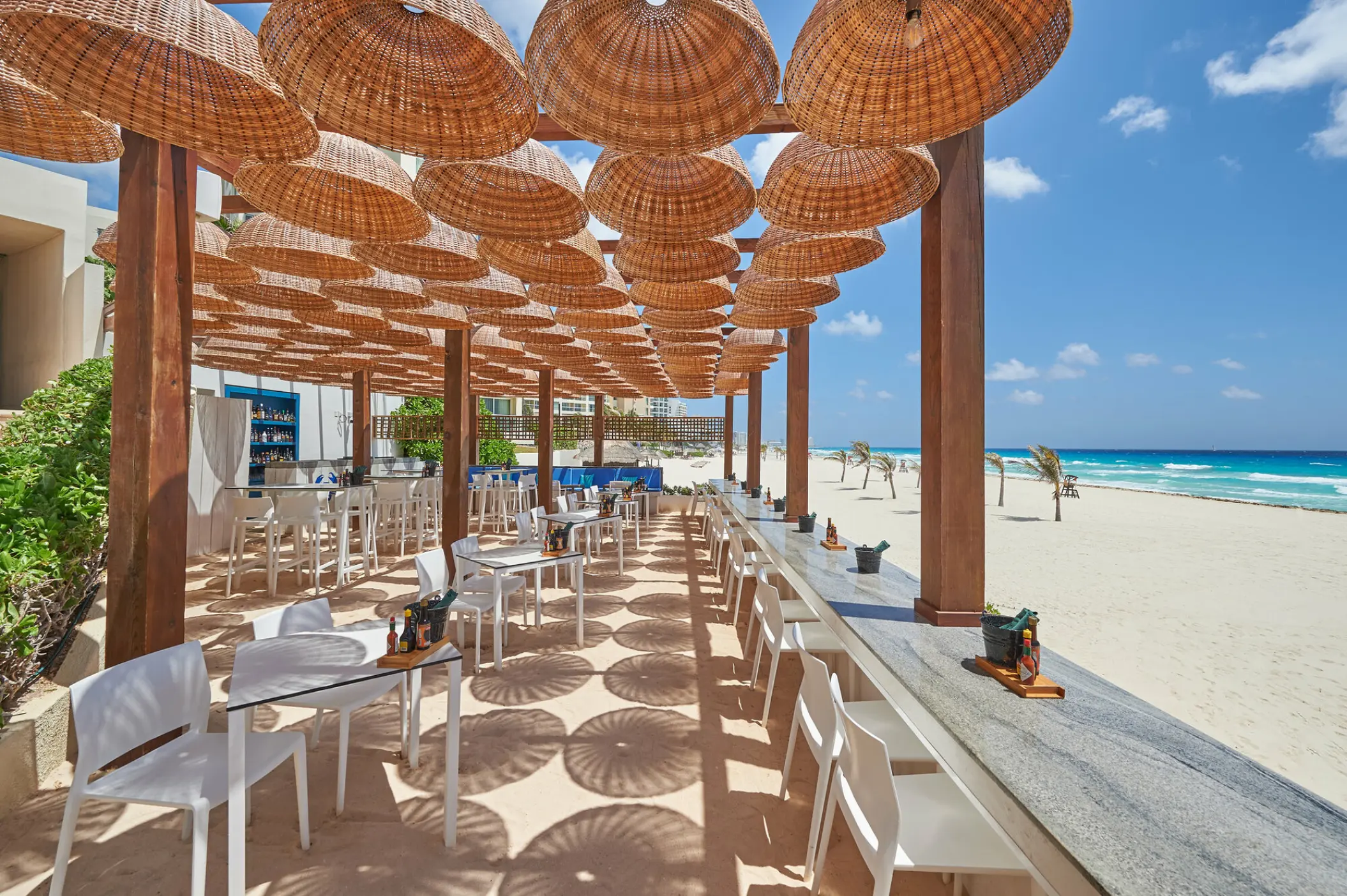 Outdoor beachfront restaurant with wicker umbrellas at Live Aqua Cancun