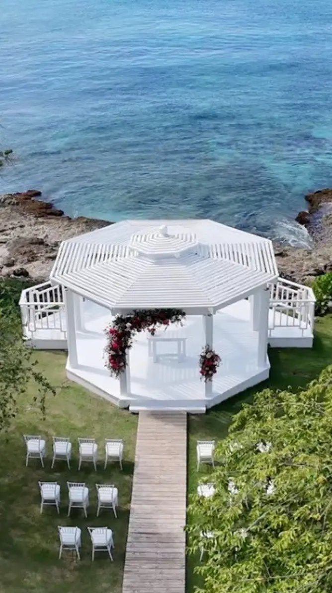Oceanfront wedding ceremony gazebo with red floral arrangements in the Dominican Republic