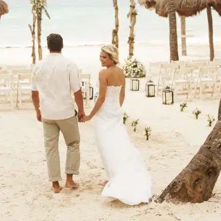 Bride and groom walking toward a beach ceremony setup at Mahekal Beach Resort, Playa Del Carmen