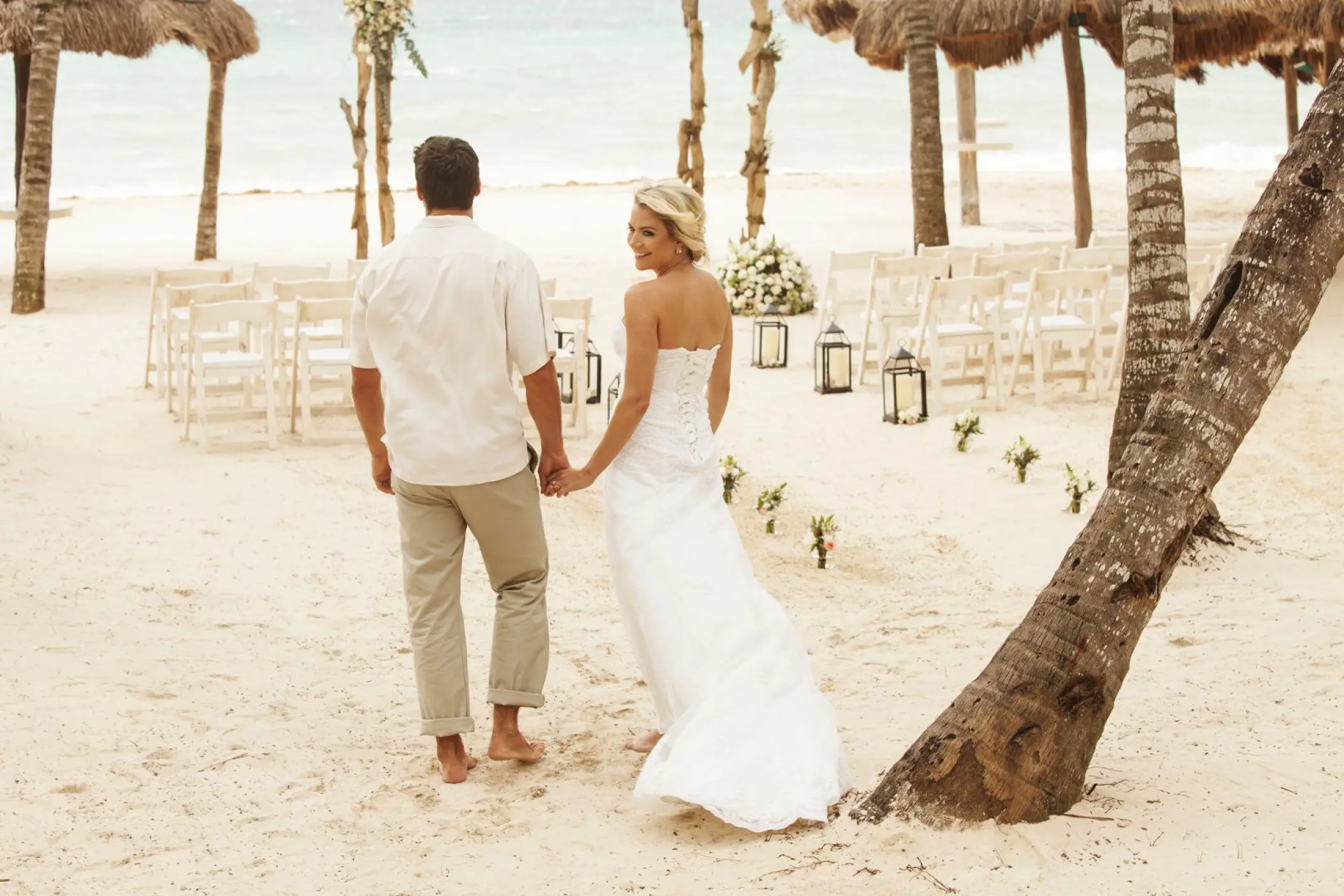Bride and groom walking toward a beach ceremony setup at Mahekal Beach Resort, Playa Del Carmen