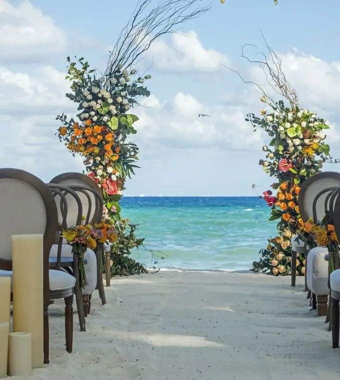 Beachfront wedding ceremony setup with floral columns at Mahekal Beach Resort, Playa Del Carmen