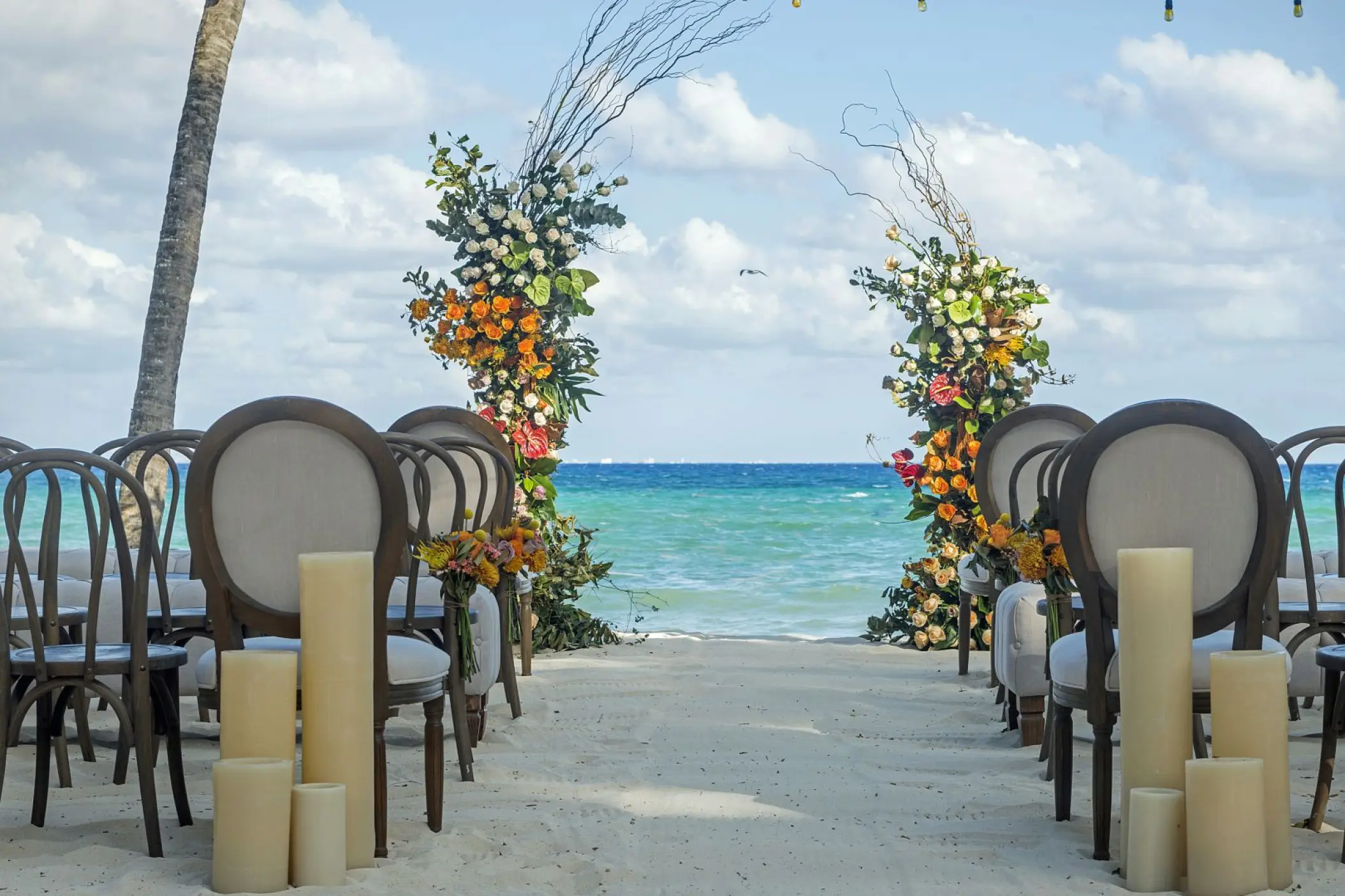 Beachfront wedding ceremony setup with floral columns at Mahekal Beach Resort, Playa Del Carmen