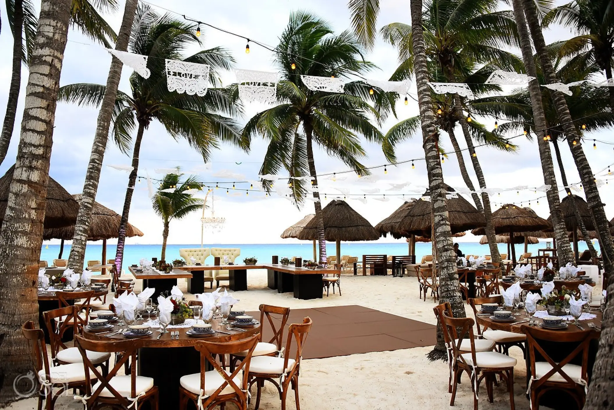 Outdoor wedding reception with round tables and palm trees at Mahekal Beach Resort, Playa Del Carmen