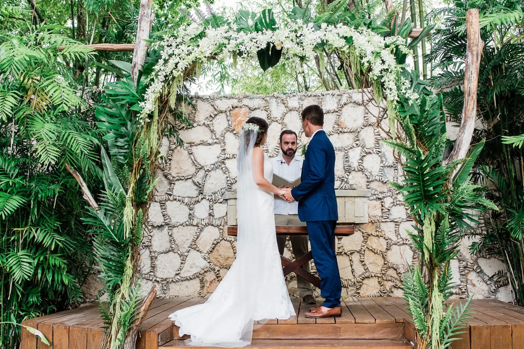 Wedding ceremony under a tropical flower arch at Mahekal Beach Resort, Playa Del Carmen