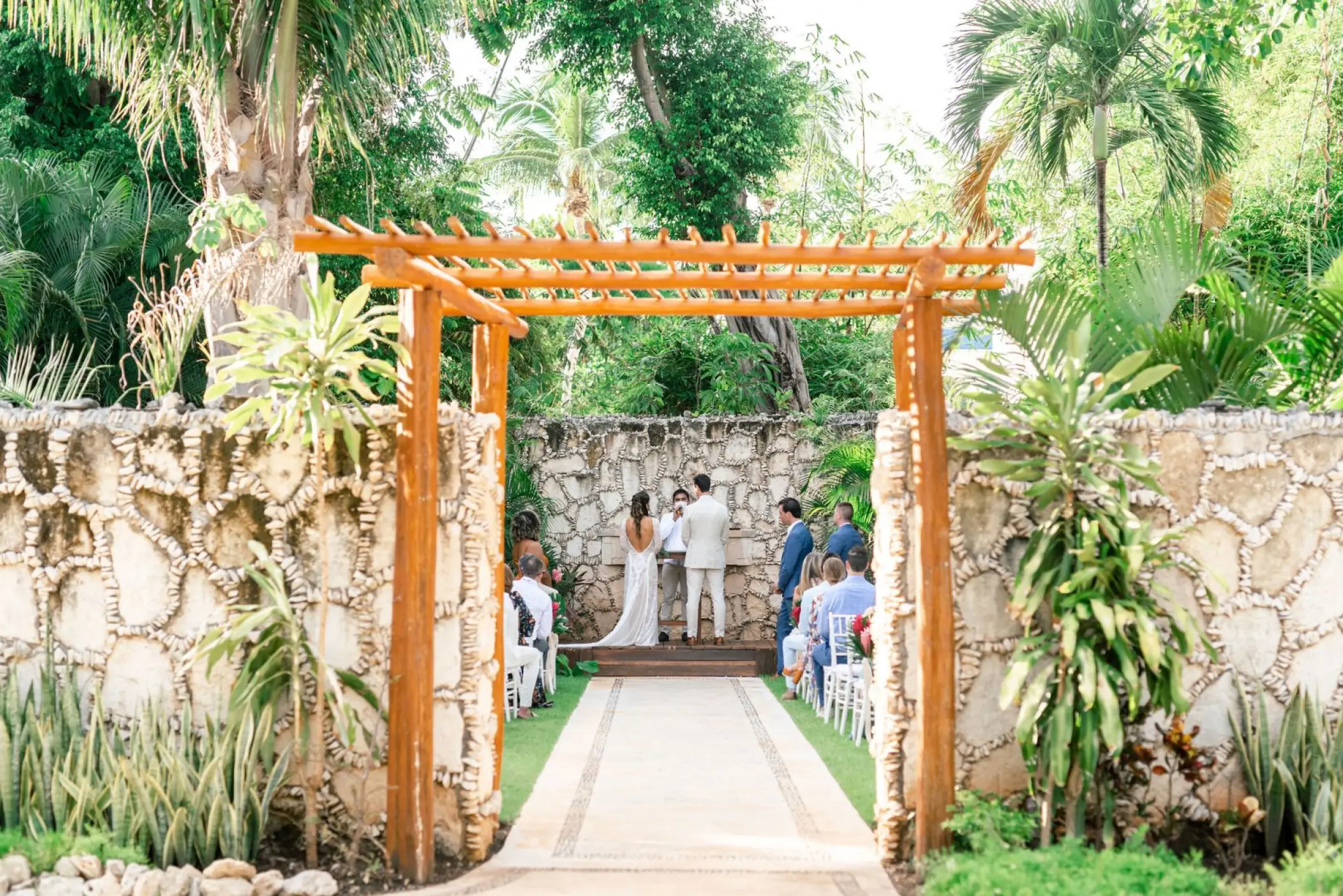Garden wedding ceremony under a wooden pergola at Mahekal Beach Resort, Playa Del Carmen