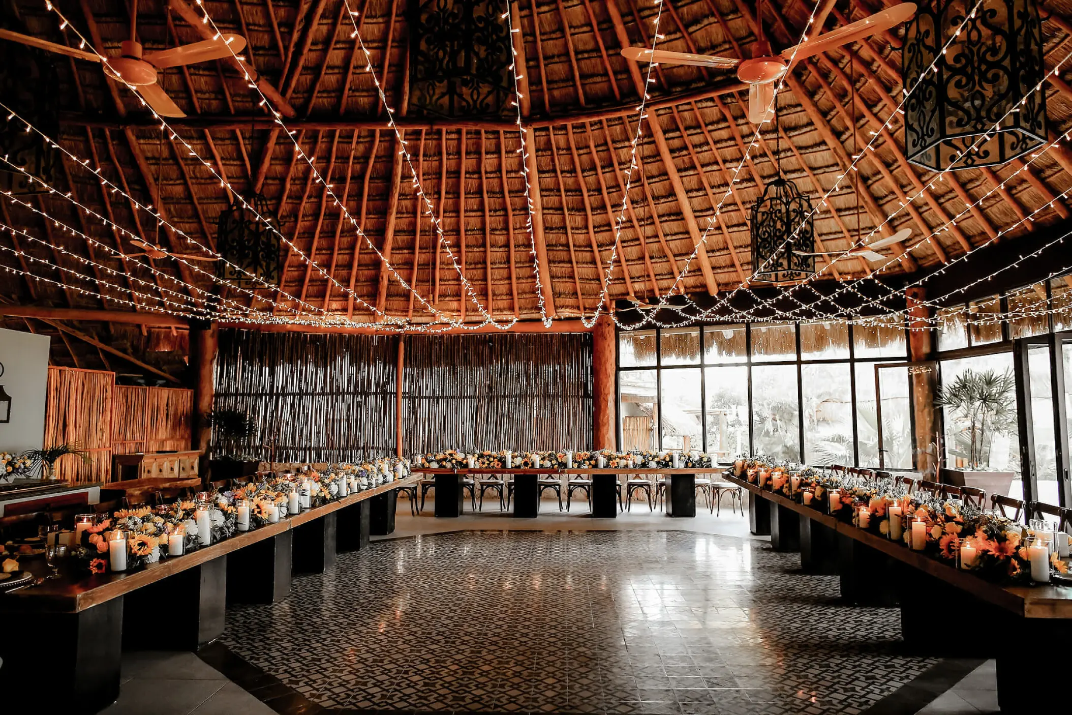 Indoor wedding reception under a thatched roof with string lights at Mahekal Beach Resort, Playa Del Carmen