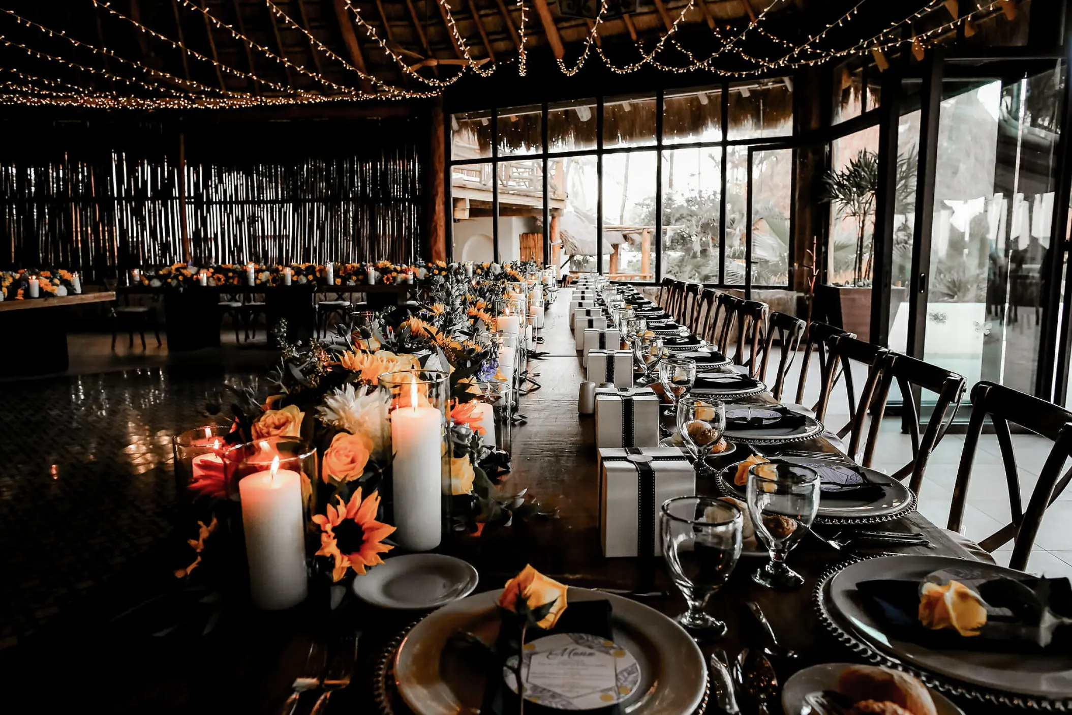 Long banquet table with sunflowers and string lights for a wedding reception at Mahekal Beach Resort, Playa Del Carmen