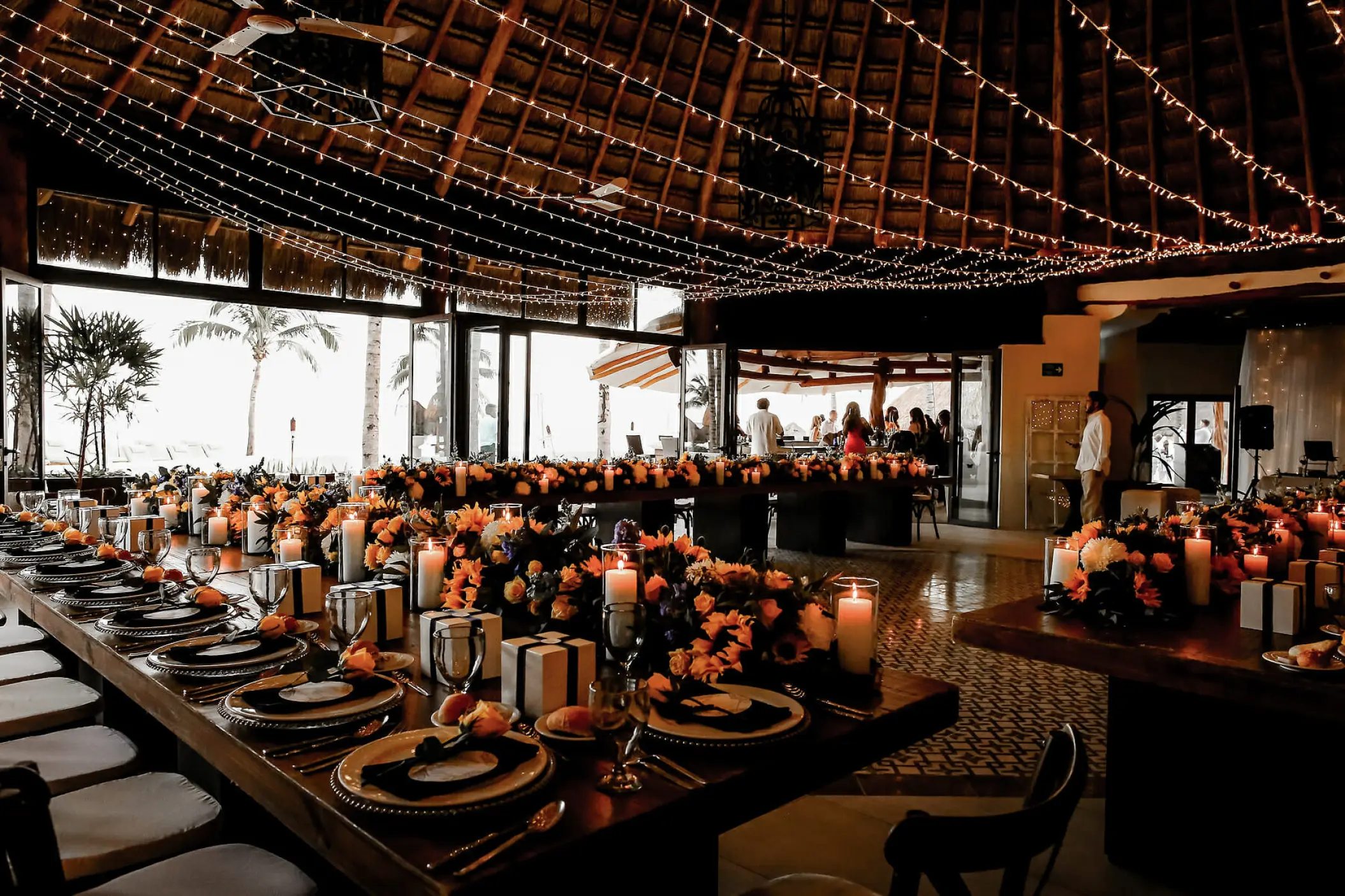 Indoor wedding reception with string lights under a thatched roof at Mahekal Beach Resort, Playa Del Carmen