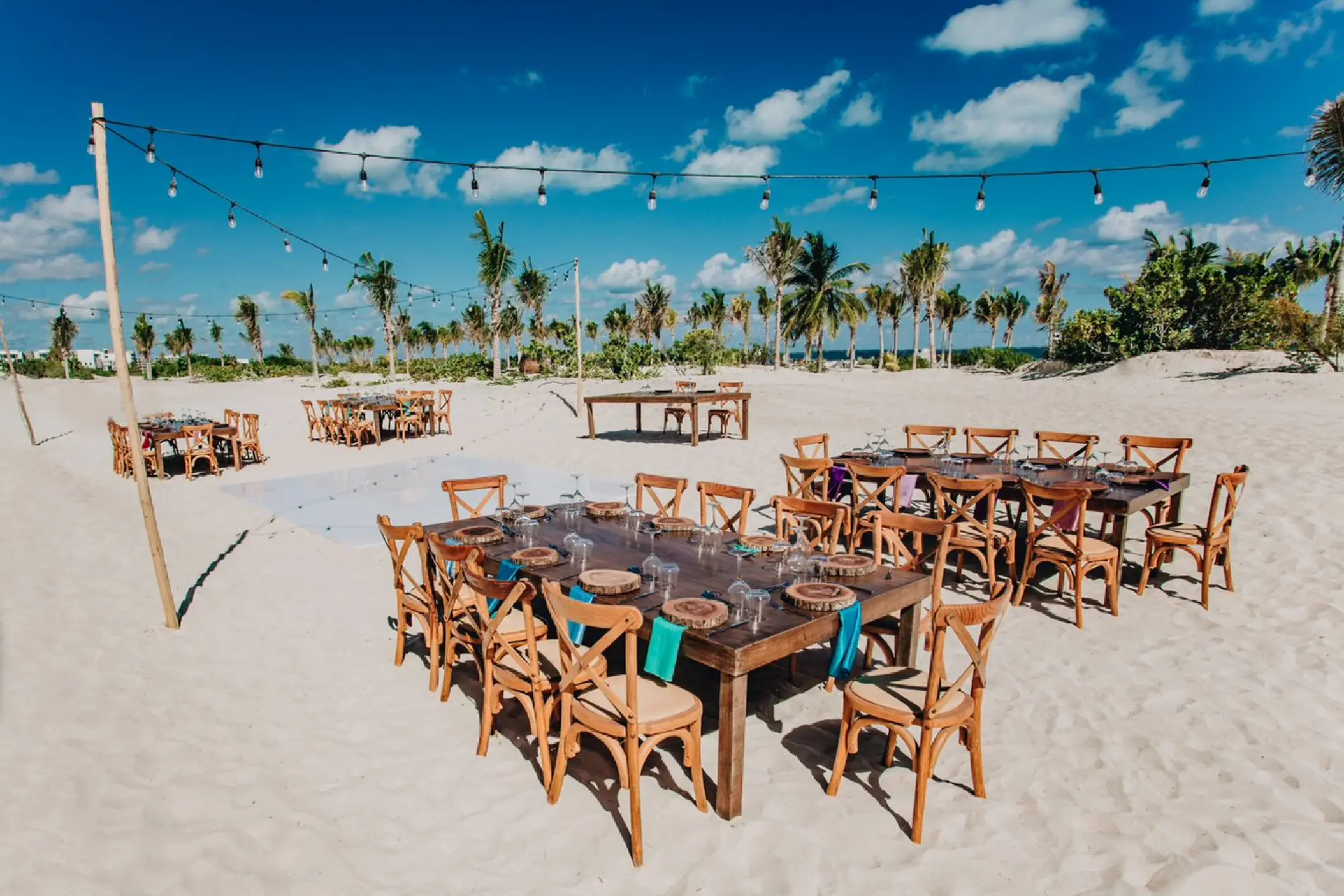 Beach wedding reception setup with wooden tables at Majestic Elegance Costa Mujeres, Cancun