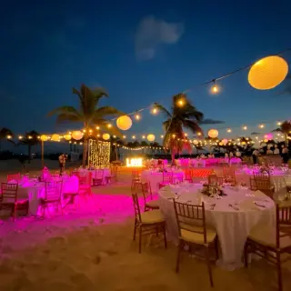 Beachfront wedding reception at night with pink lighting and paper lanterns at Majestic Elegance Costa Mujeres, Cancun