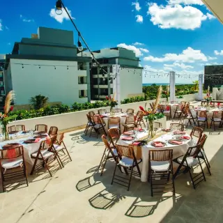 Rooftop wedding reception with round tables and string lights at Majestic Elegance, Cancun