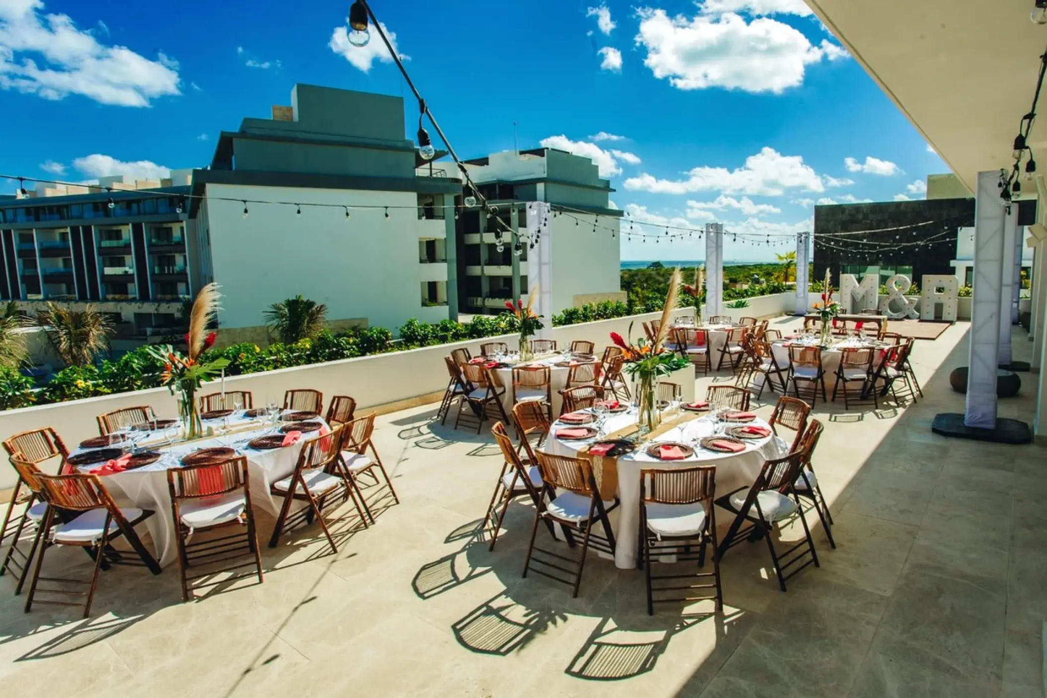 Rooftop wedding reception with round tables and string lights at Majestic Elegance, Cancun
