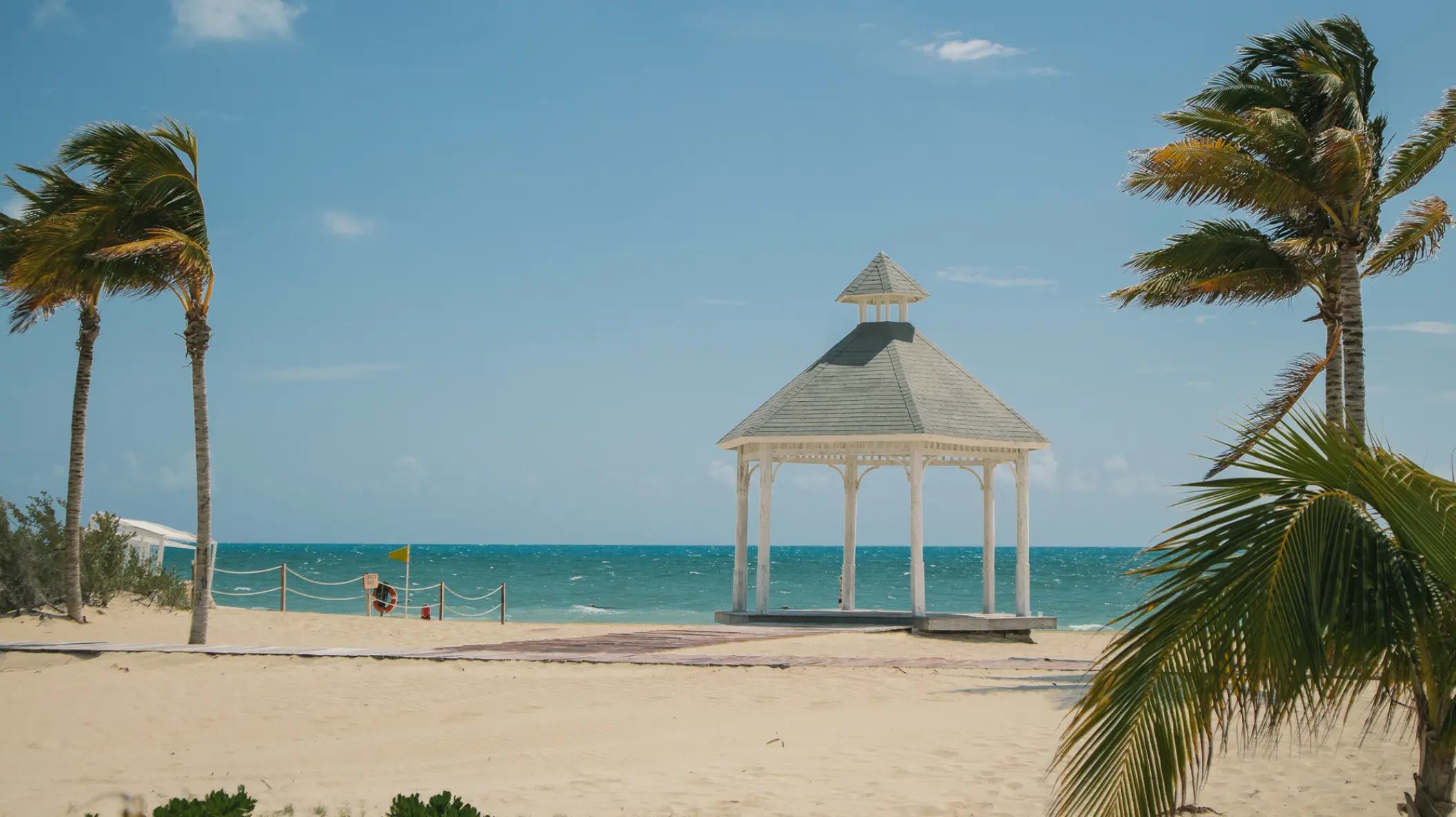 Beachfront wedding gazebo framed by palm trees at Majestic Elegance Costa Mujeres, Cancun