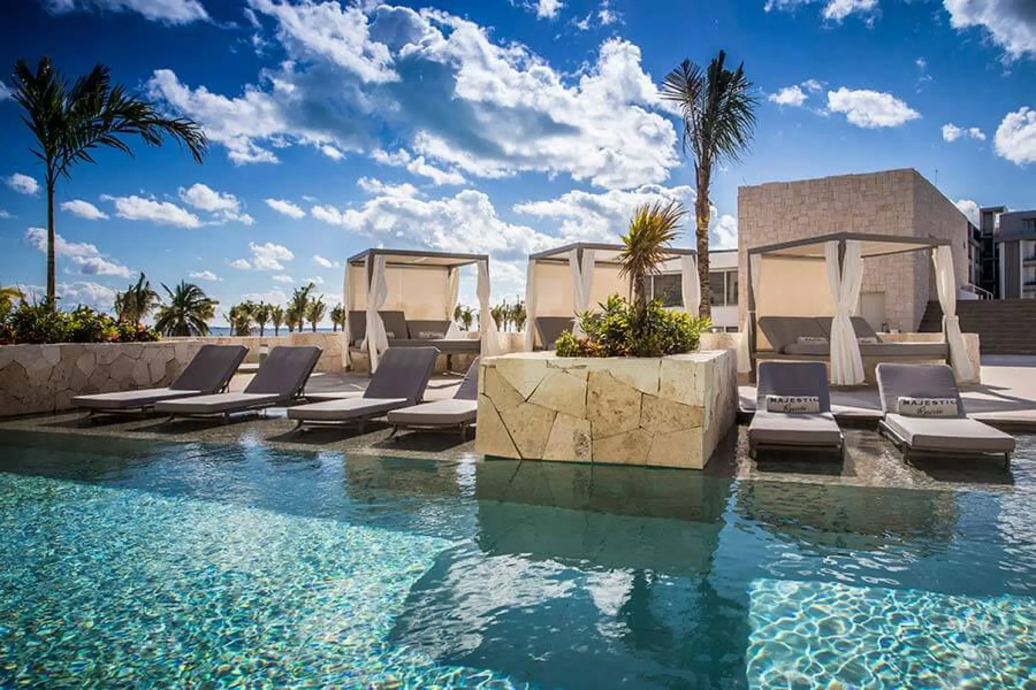 Poolside lounge chairs and cabanas at Majestic Elegance Costa Mujeres, Cancun