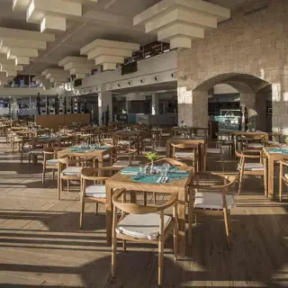 Modern indoor restaurant with wooden tables and stone arches at Majestic Elegance Costa Mujeres, Cancun