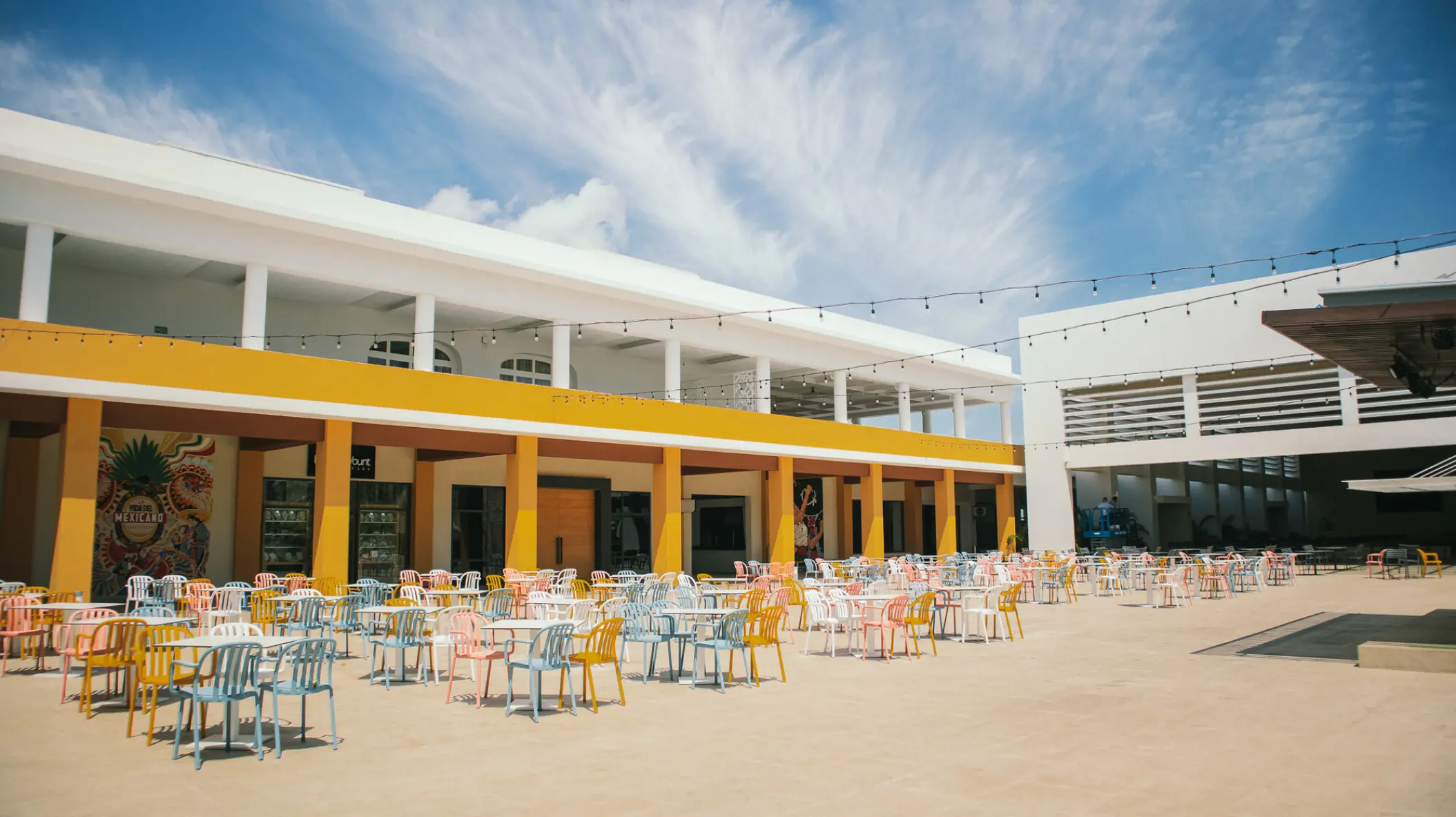 Outdoor theater seating area with colorful chairs and tables at Majestic Elegance Costa Mujeres, Cancun